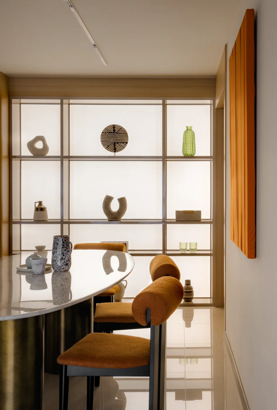 A Stellato Bianco table in a warm timber dining room, lit shelving behind