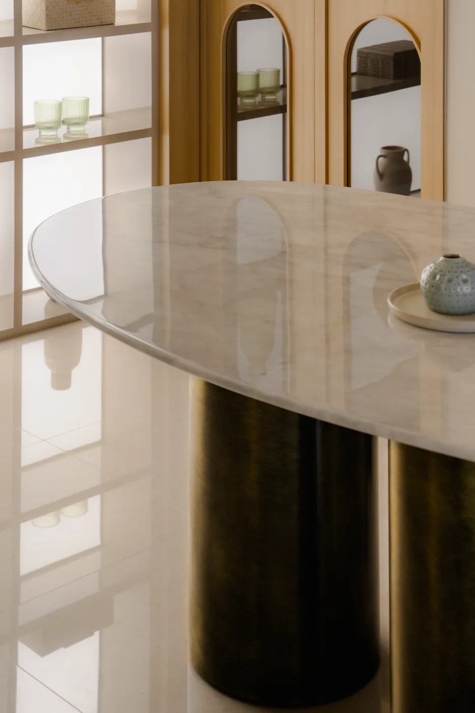 The polished edge of a Stellato Bianco oval top, brass pedestals below
